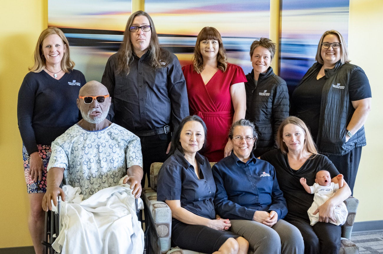 Group photo of Simulation Center staff, faculty, and two manikins.