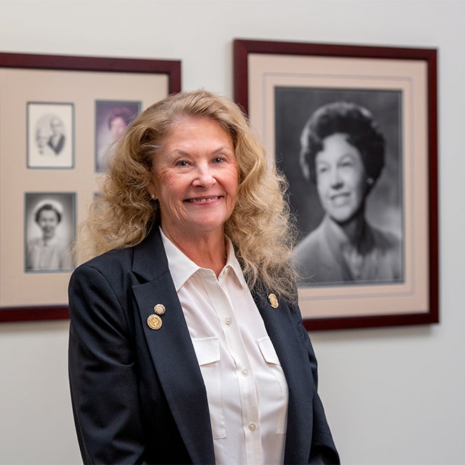 woman standing in from of portraits hanging on the wall