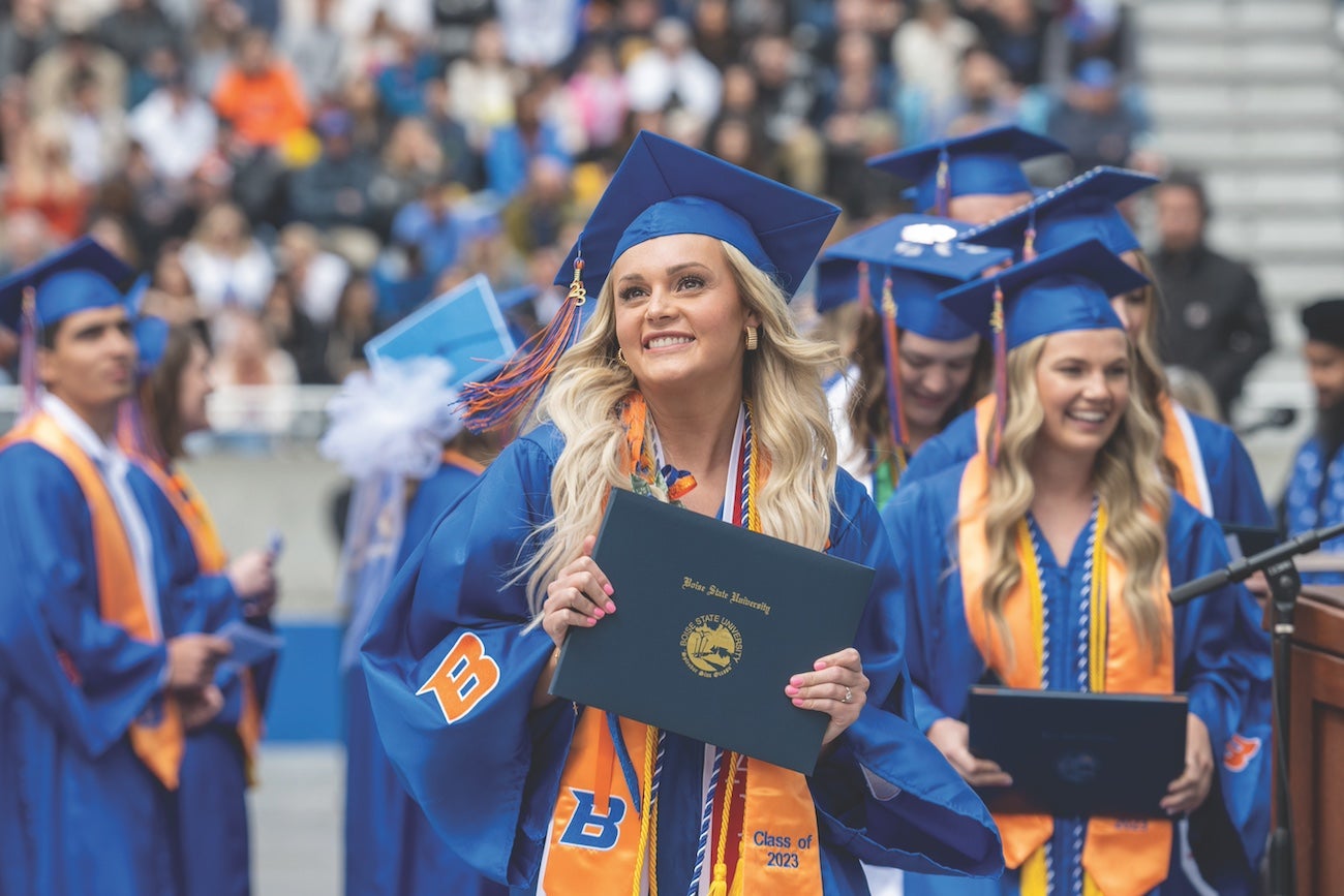 A graduate poses with a diploma