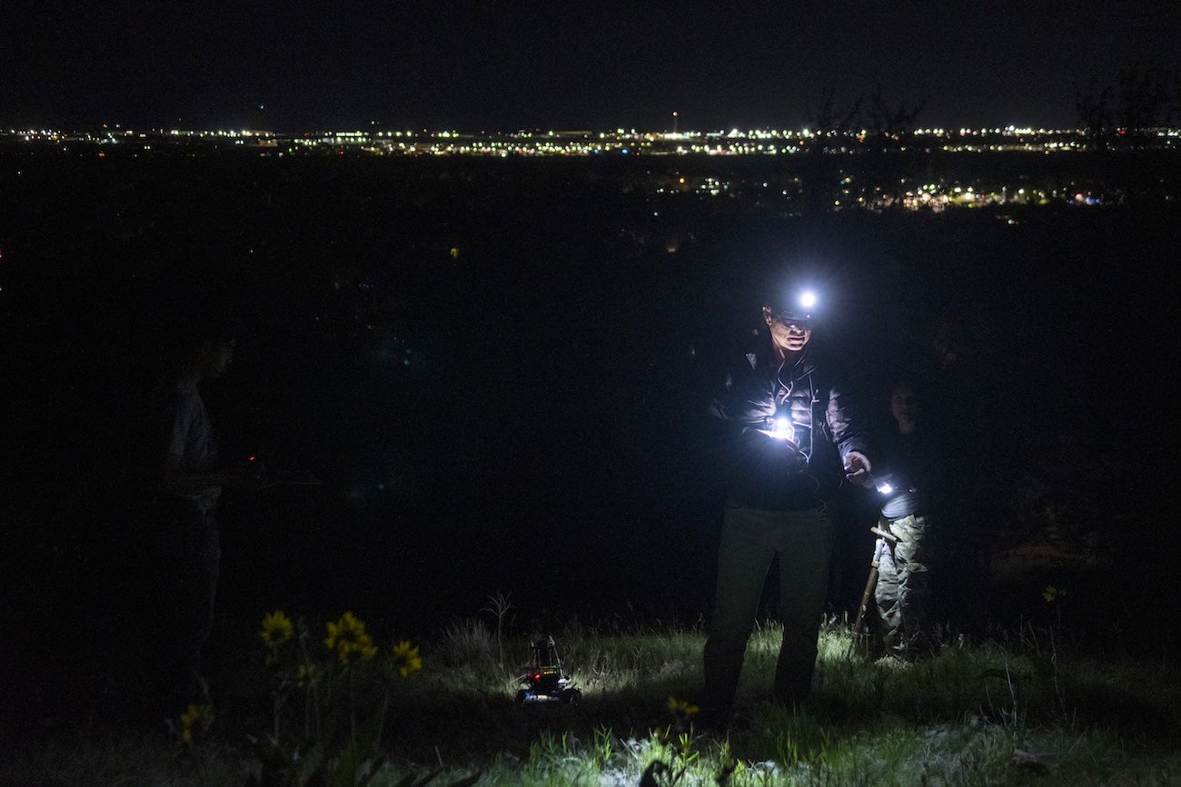 A person walks with a VR headset at night