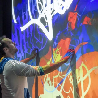 man interacts with giant wall touch screen