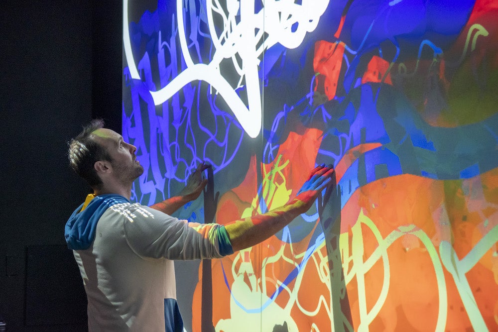 man interacts with giant wall touch screen