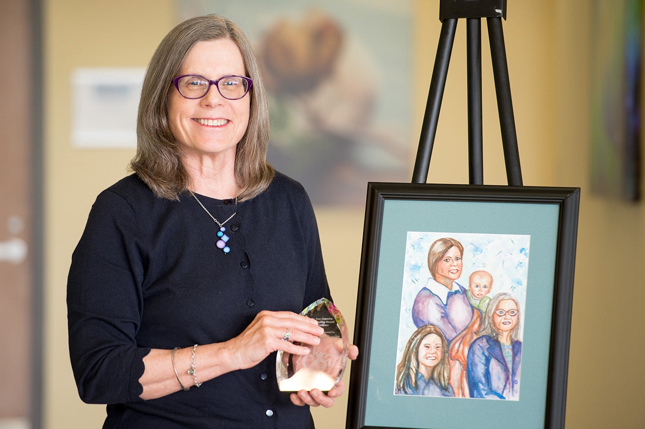 Jane Grassley poses with framed artwork and a glass award.