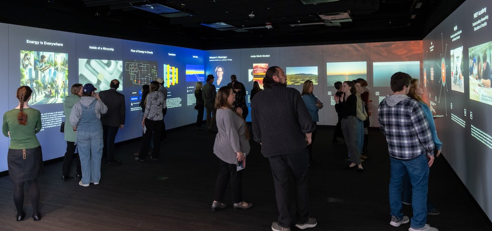 two dozen people mill in digital exhibit space