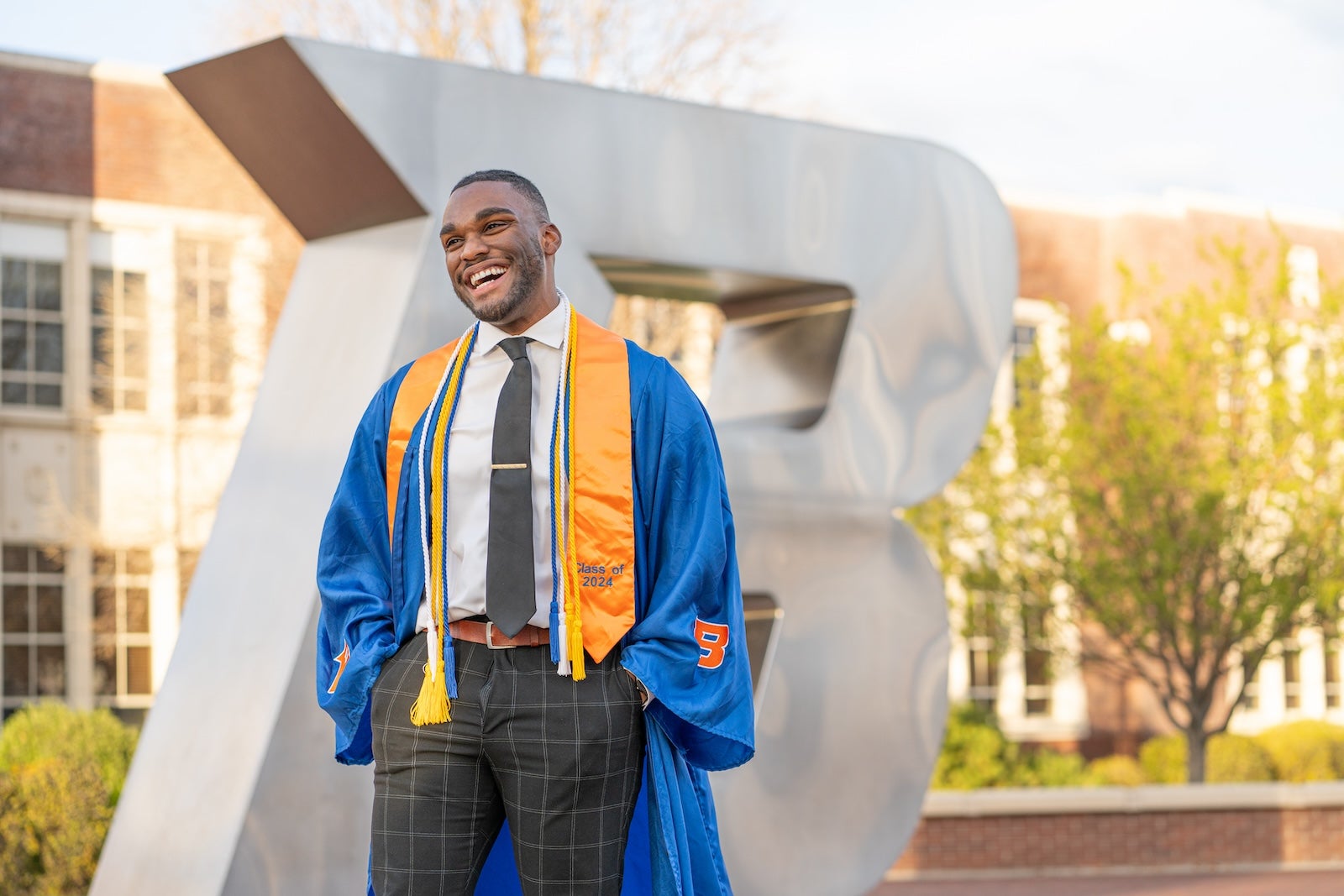 Jason Holman poses on the Boise State campus in his regalia