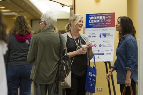 Persons stand in front of a sign board at a conference