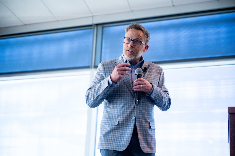 man in suit speaks into microphone