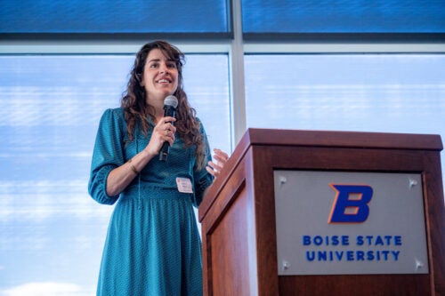 woman at podium speaks into microphone with smile