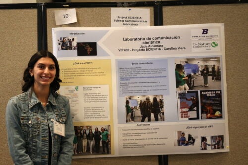 woman stands in front of research poster