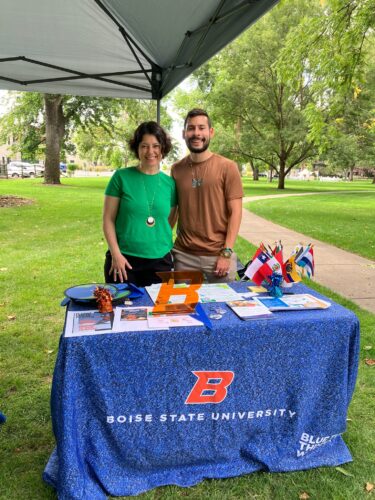 two people stand outside behind a table presenting Boise State project research