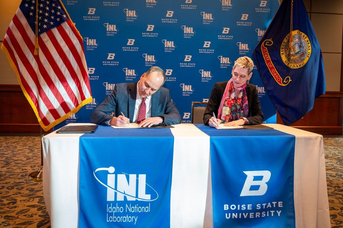 Two persons sign agreements at a table
