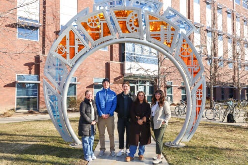 A group of persons poses at the geothermal sculpture on Boise State's campus