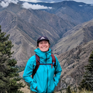 Gwen stands in raincoat in front of mountains
