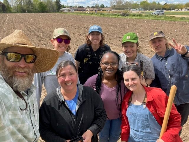 A group of persons pose in a farm field 