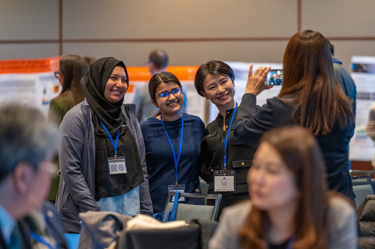 Students and a university representative pose as a person takes a picture on their phone