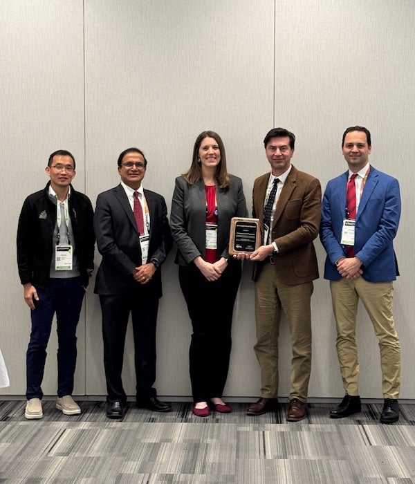 Persons pose with an award plaque