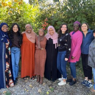 nine women stand outside in group photo
