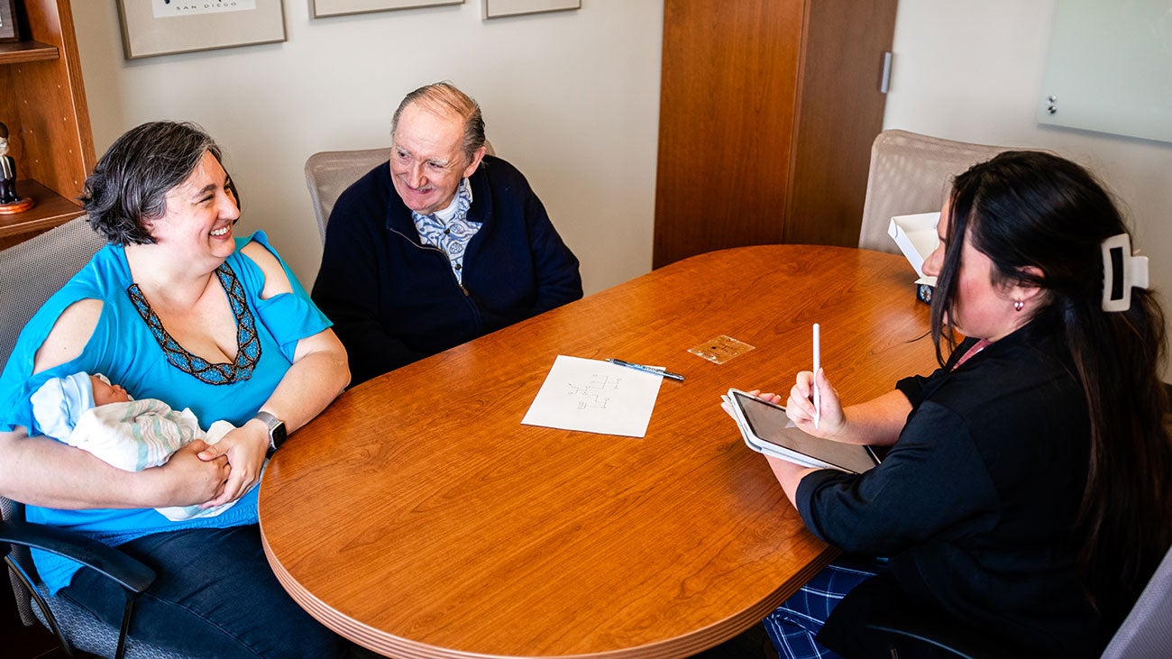 There persons gather at a table in a counseling simulation.
