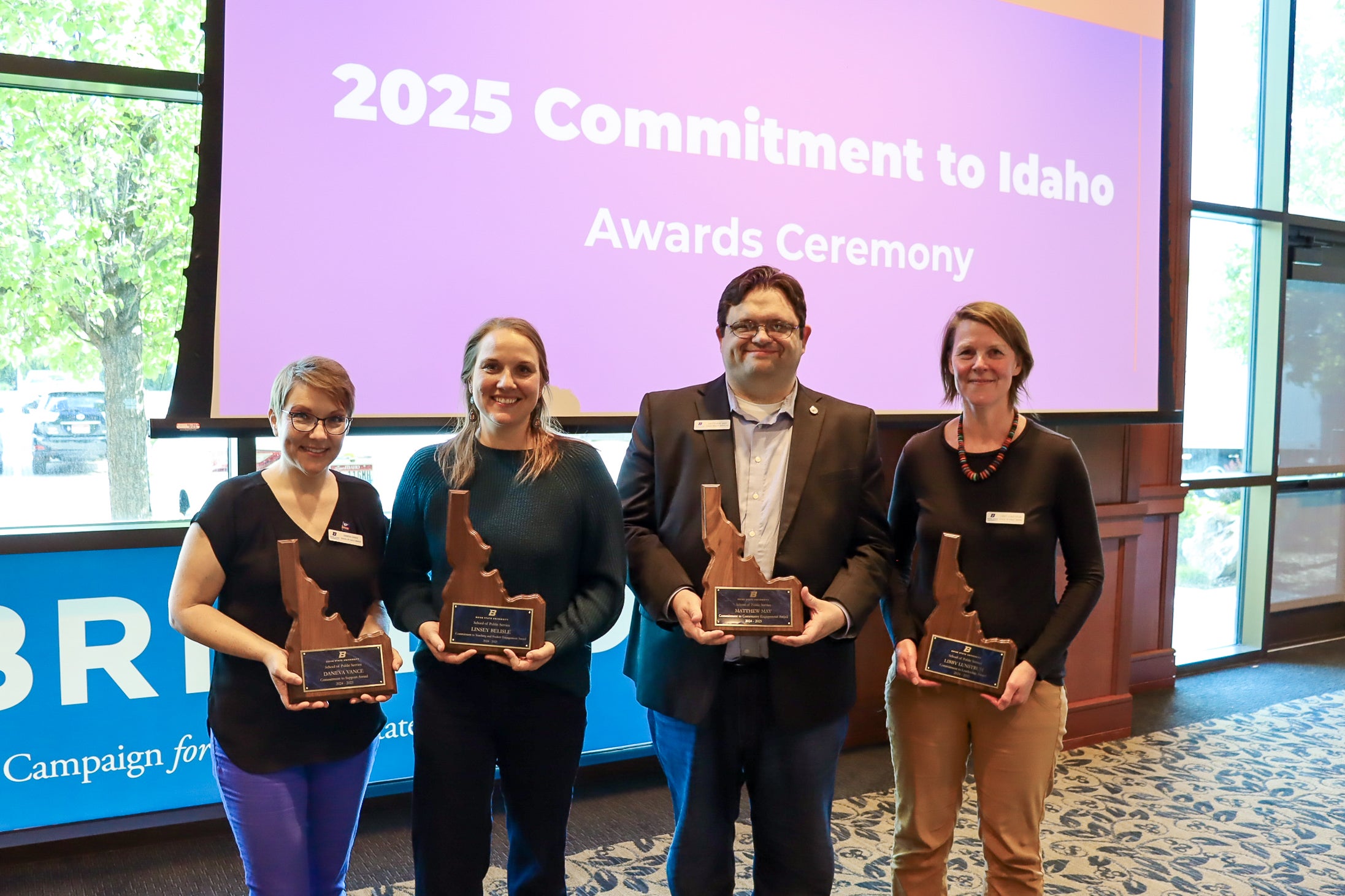 Four persons pose with awards in the shape of the state of Idaho