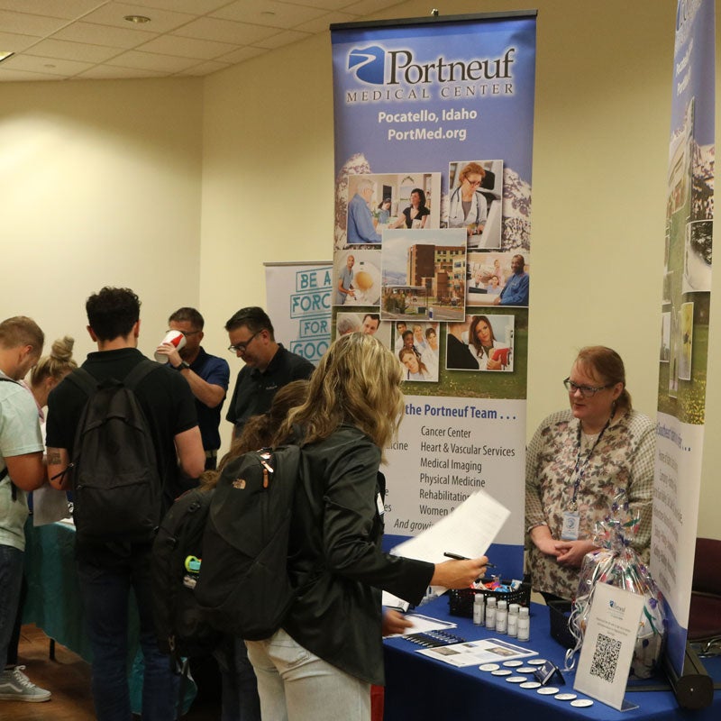 A student stands and talks with a representative at the Portneuf Medical Center table.