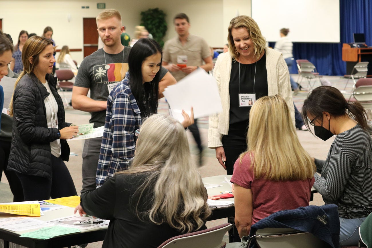 Students wait at the bank table during the poverty simulation.