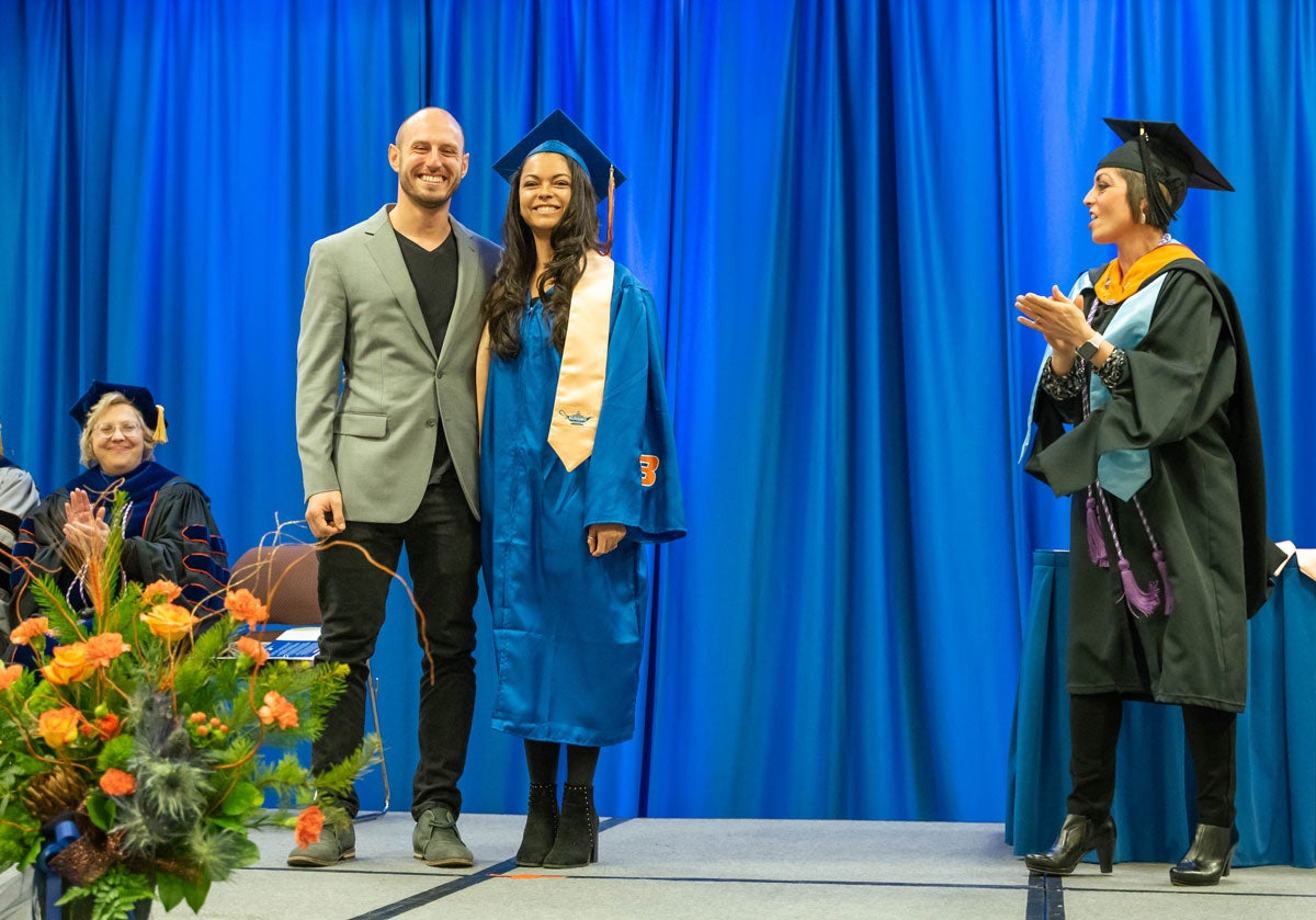 Angie Phillips claps for Ashton Bartlett, who stands on stage with her escort.