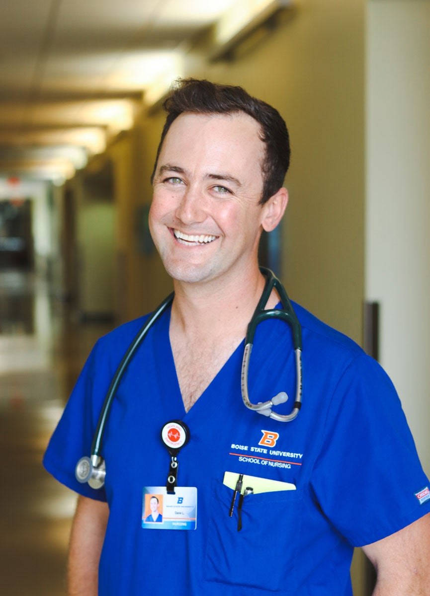 Dane Larson wears his Boise State blue scrubs and smiles with his stethoscope around his neck.