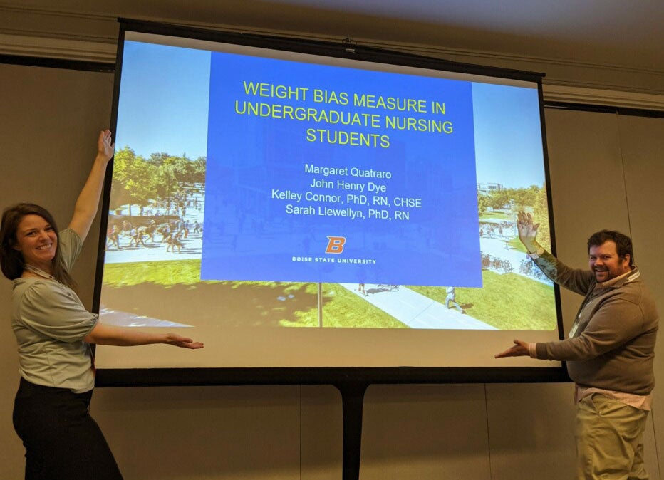 Margaret Quatraro stands with John Dye in front of a projected slide presentation of their research project.