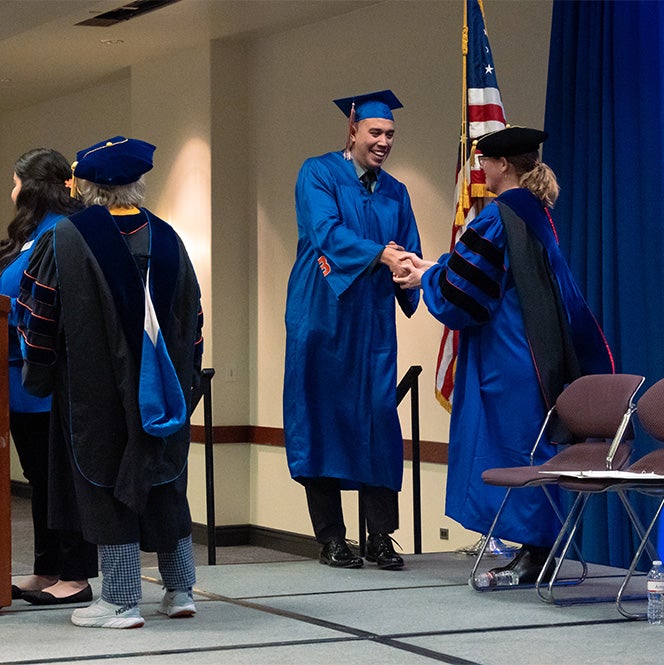 Esteban Palencia shakes a professor's hand as he walks on stage to accept his award.