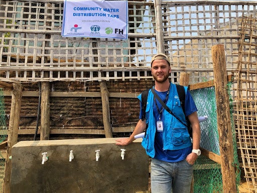 Angus stands in front of community water distribution taps