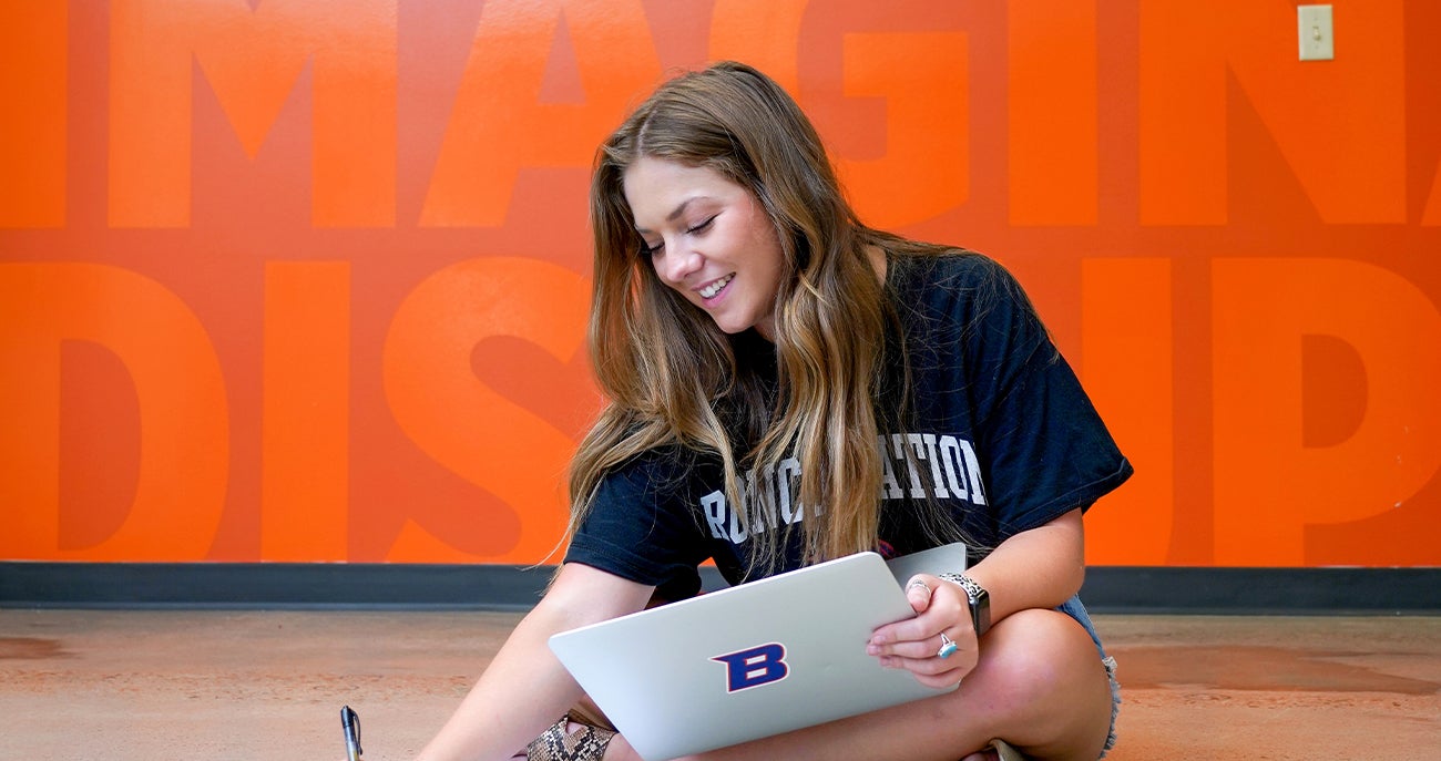 Female student sits on the ground and studies.