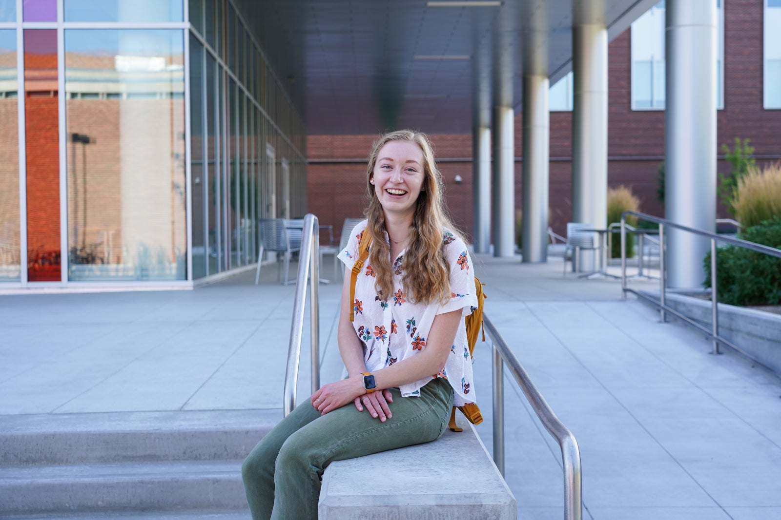 Clara Adams sits on outside steps, smiling into the camera.