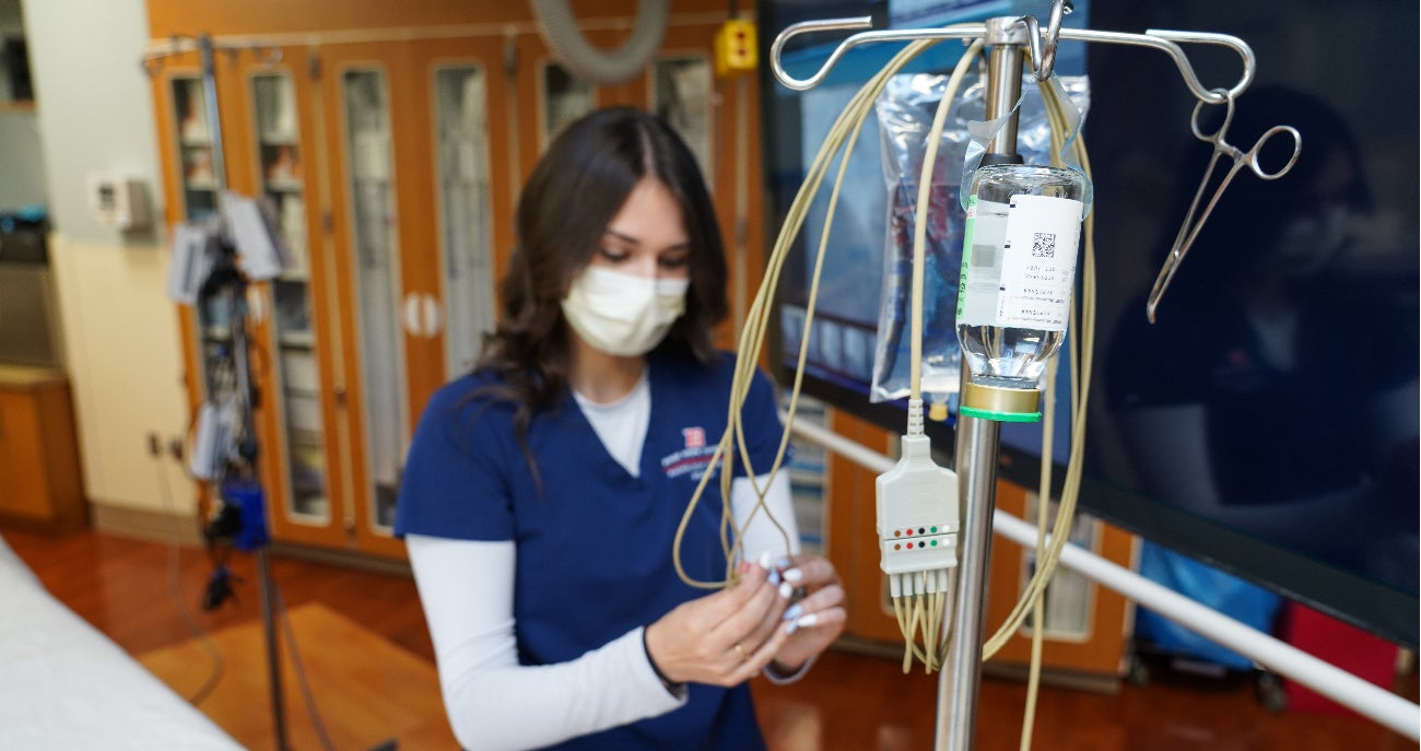 Advanced medical imaging program student stands next to medical equipment