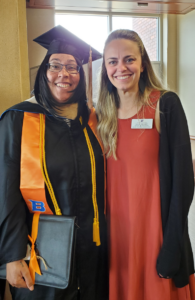 Ebony Bains in graduation regalia stands next to Rachel Bagnard. 
