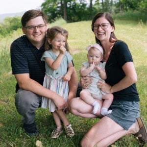 Jerid Rimbey, his wife and two daughters sitting in a grass field