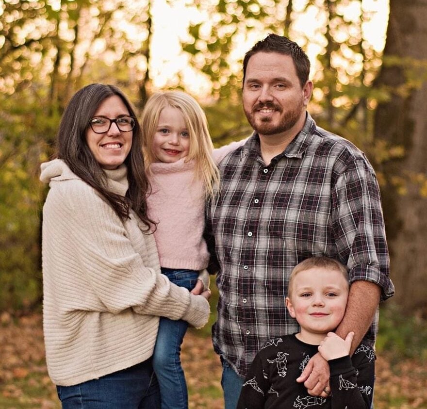 Sierra Willis pictured with her family with fall foliage in the background.