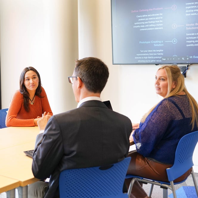 Three ISC students sitting in a conference room engaging in a conversation