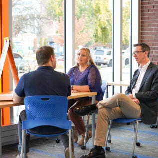 Three adults sit around a square table