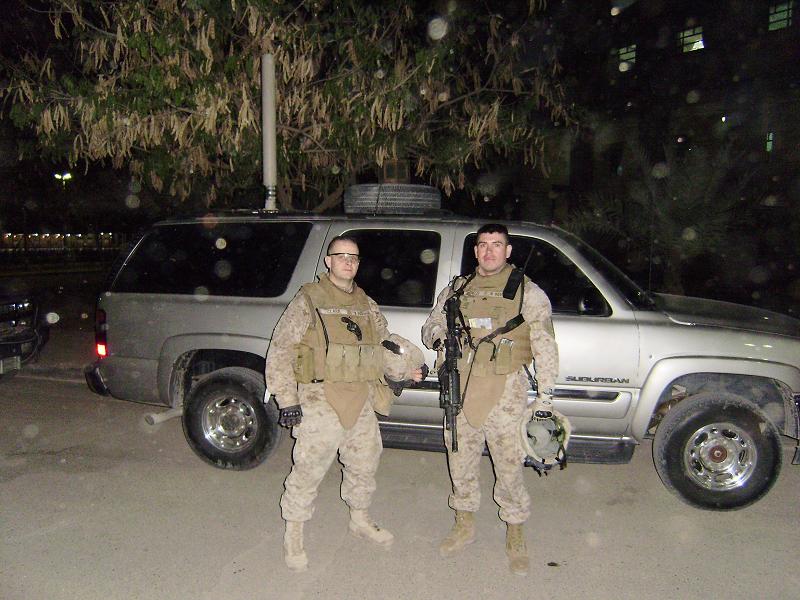 Two marines posing for a photo in front of a car