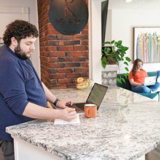 A man working on a laptop at a counter, getting his business degree online
