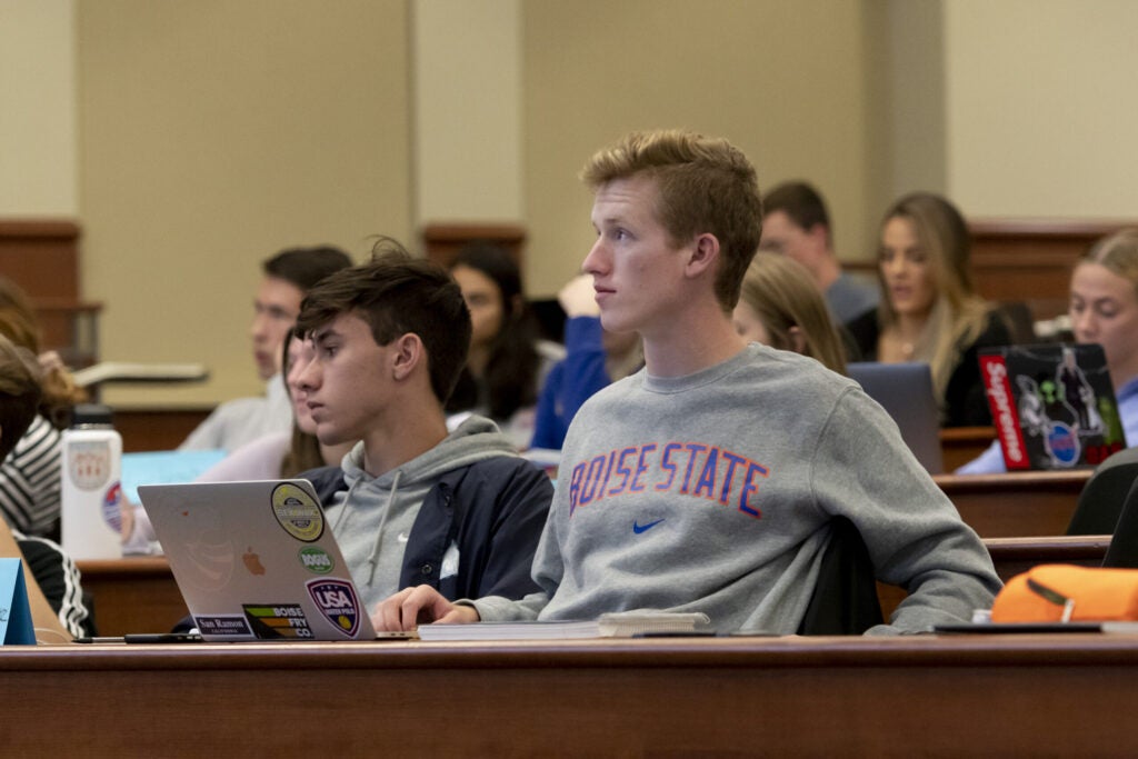 Students sit in a lecture hall watching a presentation
