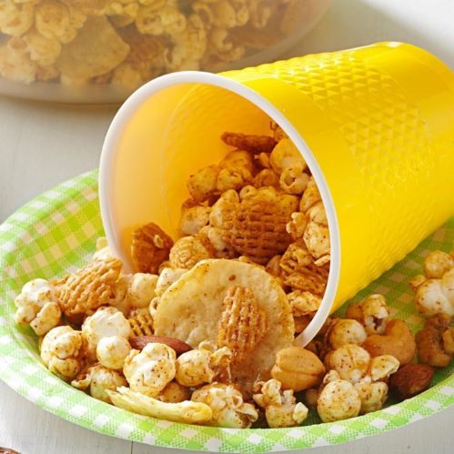 A colorful mix of snacks spills from a yellow cup onto a plate.
