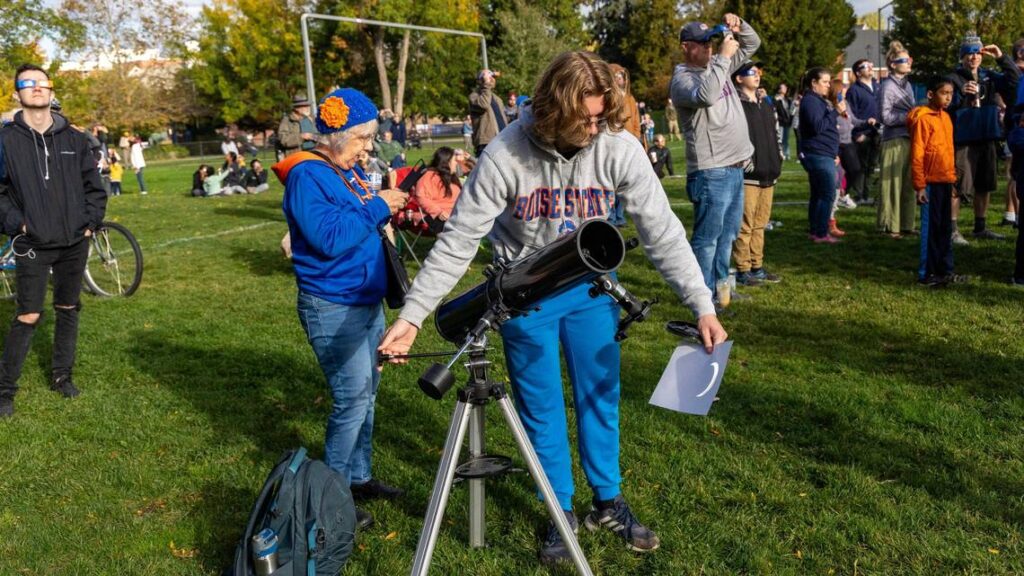 Boise State freshman Hunter Gregory uses a telescope to reflect an image of the annular solar eclipse onto a sheet of paper