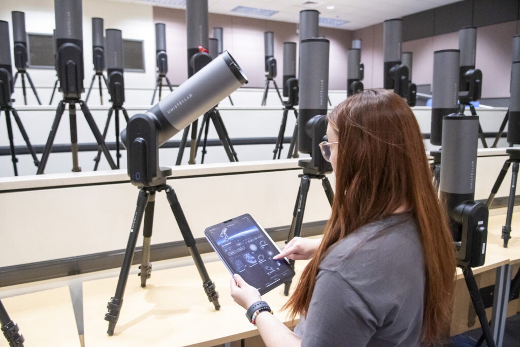 Woman controlling telescope with tablet