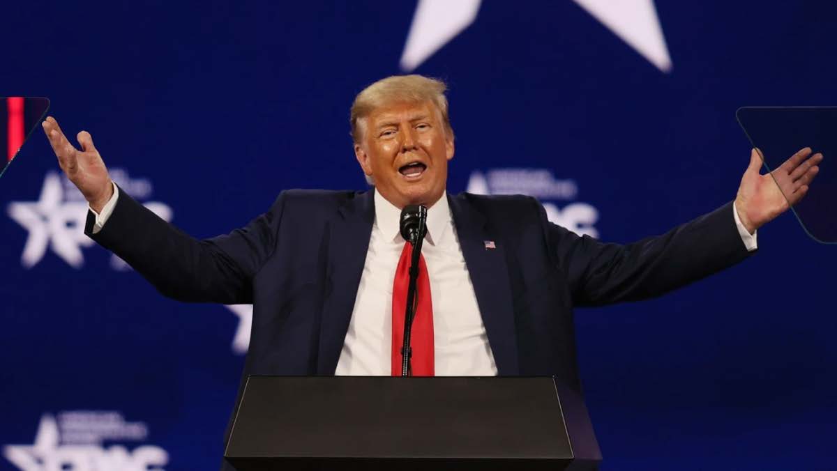 Donald Trump standing behind a podium holding his hands in the air
