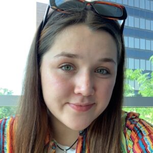 Close up of Jaelahna, a brunette girl smiling with a multicolored shirt.