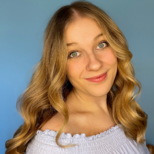 Lydia Sophia smiles at the camera in front of a blue background