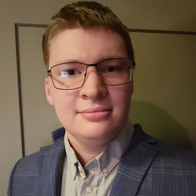 Darin wearing glasses, a grey button-up, and a blue sports coat.