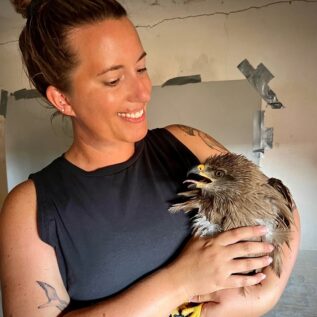 IRES student holding black kite at trapping station after taking measurements