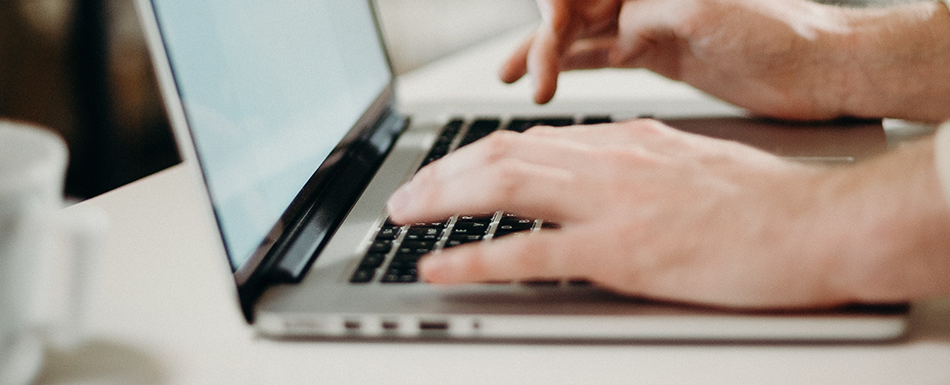 A person types on a laptop keyboard.